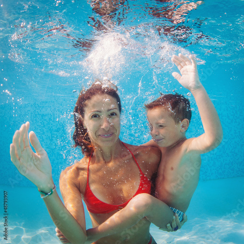 Photo: Mother and son having fun underwater in swimming pool. Mother and son having fun underwater in swimming pool.