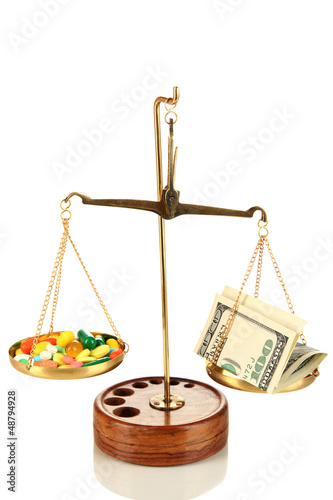Photo: Pills and money in scales isolated on white Pills and money in scales isolated on white