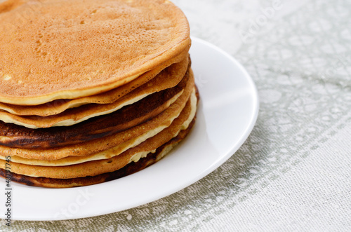 Photo: White plate with pankakes stack on the kitchen table White plate with pankakes stack on the kitchen table