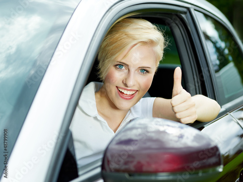 Photo: Beautiful woman shows thumbs up in her new car Beautiful woman shows thumbs up in her new car