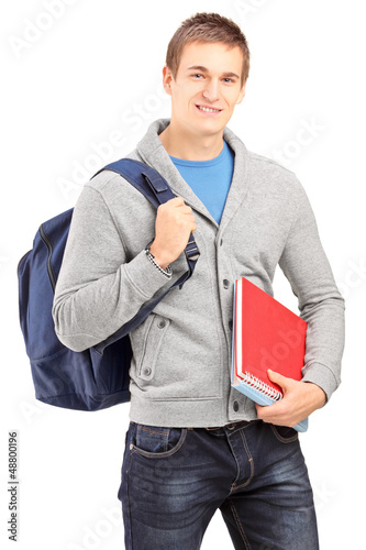 Photo: Smiling male student holding backpack and books Smiling male student holding backpack and books
