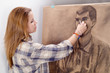 Young female artist drawing man portrait in her art studio