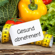 Gemüse auf Holz mit Zettel und Massband GESUND ABNEHMEN