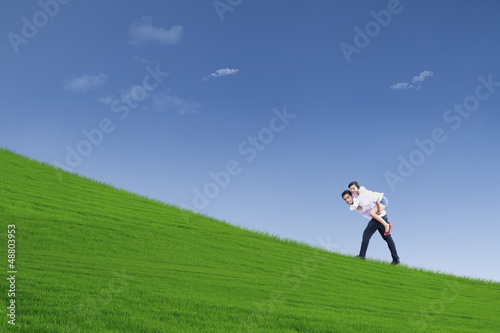 Photo: Guy giving piggyback ride under blue sky Guy giving piggyback ride under blue sky