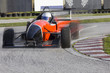 Red bolide driving at high speed in circuit.