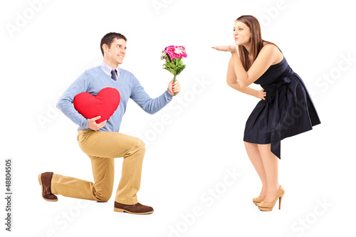 Photo: Male on knee giving a heart and flowers to a woman blowing him a Male on knee giving a heart and flowers to a woman blowing him a