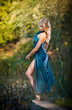 attractive women in a blue long dress at sunset in a forest