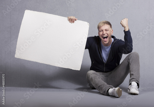 Photo: Happy man holding white empty panel. Happy man holding white empty panel.