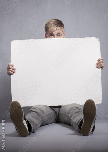 Photo: Upset man holding white empty panel. Upset man holding white empty panel.