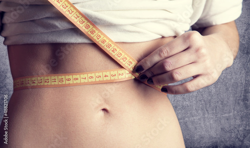 Photo: Beautiful and strong women's abs with metre. Studio shot. Beautiful and strong women's abs with metre. Studio shot.