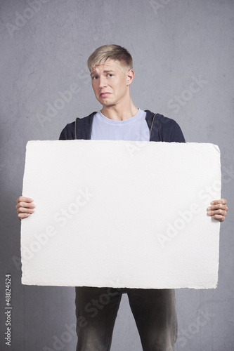 Photo: Unhappy man showing white blank panel. Unhappy man showing white blank panel.