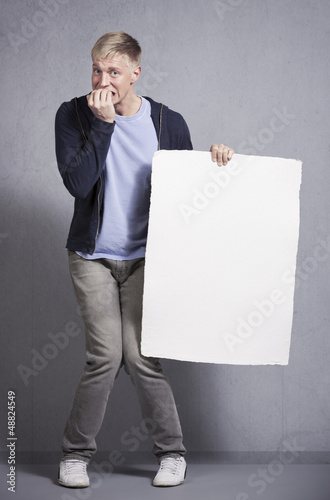 Photo: Miserable man holding white empty signboard. Miserable man holding white empty signboard.