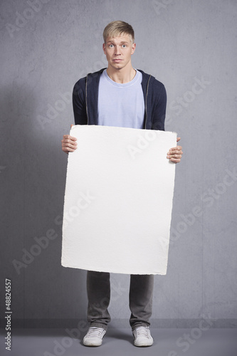 Photo: Worried man holding white empty panel. Worried man holding white empty panel.