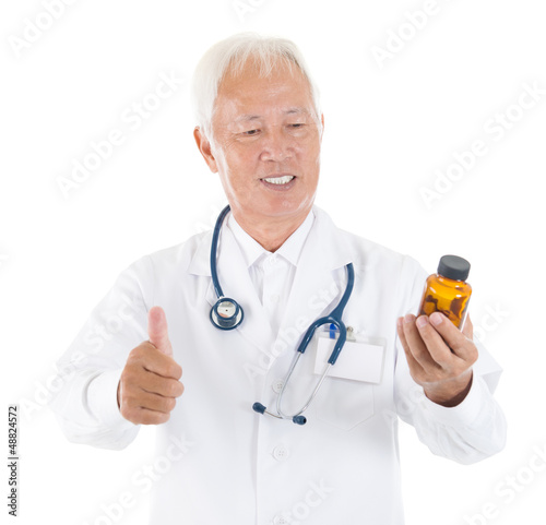 Photo: Asian senior medical doctor holding a bottle of pills Asian senior medical doctor holding a bottle of pills