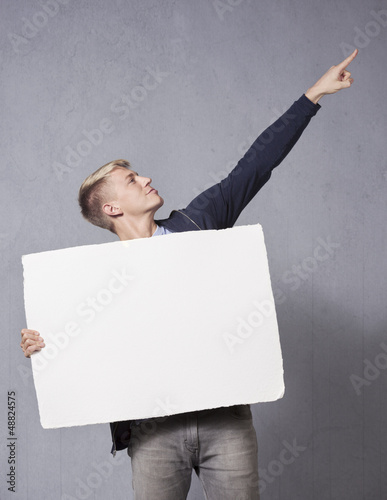 Photo: Cheerful man holding white blank signboard. Cheerful man holding white blank signboard.