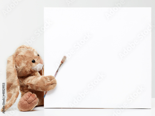 Photo: Stuffed bunny peeking behind blank board Stuffed bunny peeking behind blank board