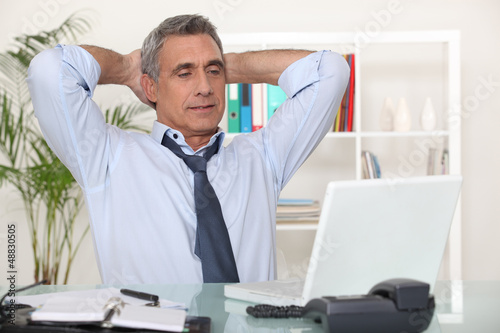 Photo: Businessman stretching at his desk Businessman stretching at his desk
