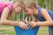 Two little girls drink clear water from drinking bowl