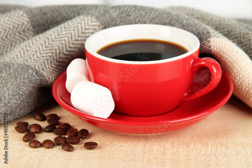 Photo: cup of coffee with scarf on table in room cup of coffee with scarf on table in room