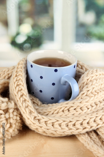 Photo: cup of tea with scarf on table in room cup of tea with scarf on table in room