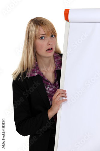 Photo: Shocked blond woman stood by blank flip chart Shocked blond woman stood by blank flip chart