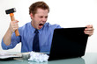A businessman about to smash his laptop with a hammer.
