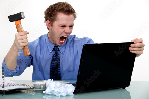 Photo: A businessman about to smash his laptop with a hammer. A businessman about to smash his laptop with a hammer.
