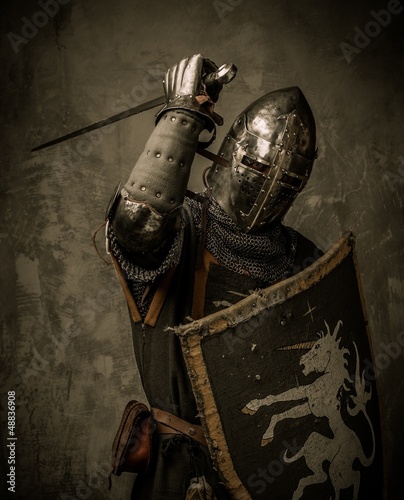 Photo: Medieval knight with sword and shield against stone wall Medieval knight with sword and shield against stone wall