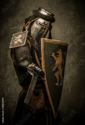 Photo: Medieval knight with sword and shield against stone wall Medieval knight with sword and shield against stone wall