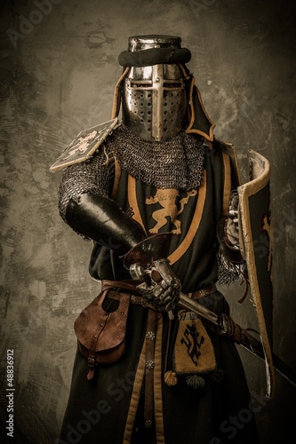 Photo: Medieval knight with sword and shield against stone wall Medieval knight with sword and shield against stone wall