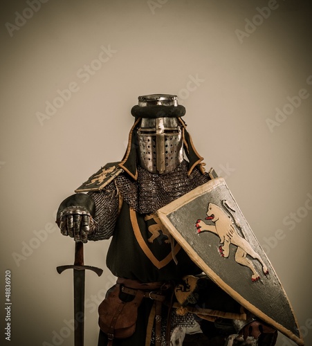 Photo: Kneeled medieval knight with sword and shield Kneeled medieval knight with sword and shield