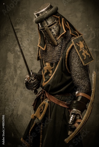 Photo: Medieval knight with sword and shield against stone wall Medieval knight with sword and shield against stone wall
