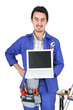 30 years old artisan showing a laptop in a room full of tools