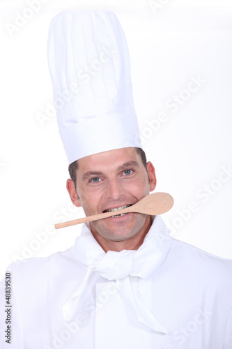 Photo: male cook with a wooden spoon in the mouth male cook with a wooden spoon in the mouth