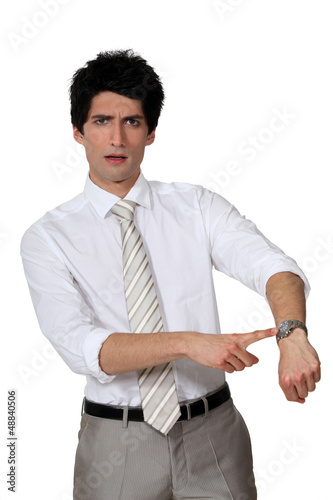 Photo: Businessman angrily pointing to his watch Businessman angrily pointing to his watch