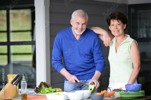 Photo: Middle-aged couple cooking outdoors together Middle-aged couple cooking outdoors together
