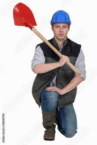 Photo: Man with spade kneeling Man with spade kneeling