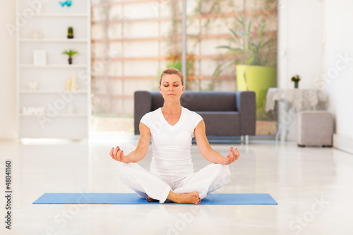Photo: middle aged woman doing yoga meditation at home middle aged woman doing yoga meditation at home