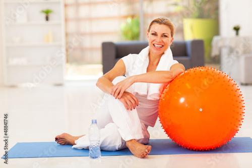 Photo: happy senior woman resting on mat after exercise at home happy senior woman resting on mat after exercise at home