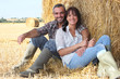 Couple sitting in front of haystack