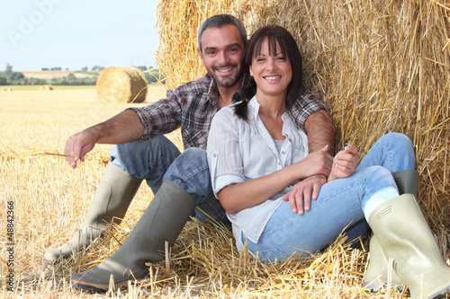 Photo: Couple sitting in front of haystack Couple sitting in front of haystack
