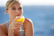 Woman enjoying glass of orange juice by the sea