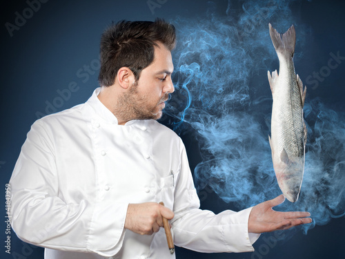 Photo: Male chef with levitating seabass fish Male chef with levitating seabass fish