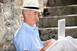 Elderly man sat on steps with laptop