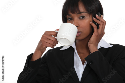 Photo: Businesswoman drinking coffee whilst on the telephone Businesswoman drinking coffee whilst on the telephone