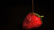 Melted chocolate being poured over strawberry