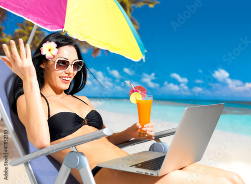 Photo: Happy woman on the beach with a laptop Happy woman on the beach with a laptop