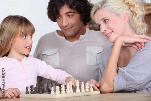 Photo: Parents and daughter playing chess Parents and daughter playing chess