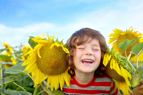 Photo: happy sweet little boy in field of sunflowers happy sweet little boy in field of sunflowers