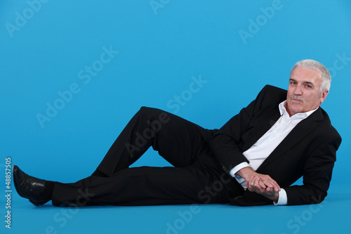 Photo: Grey-haired businessman laying on the floor Grey-haired businessman laying on the floor